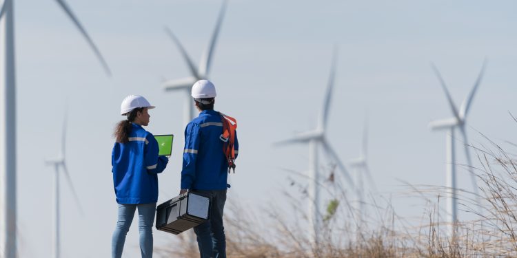two workers view wind turbine